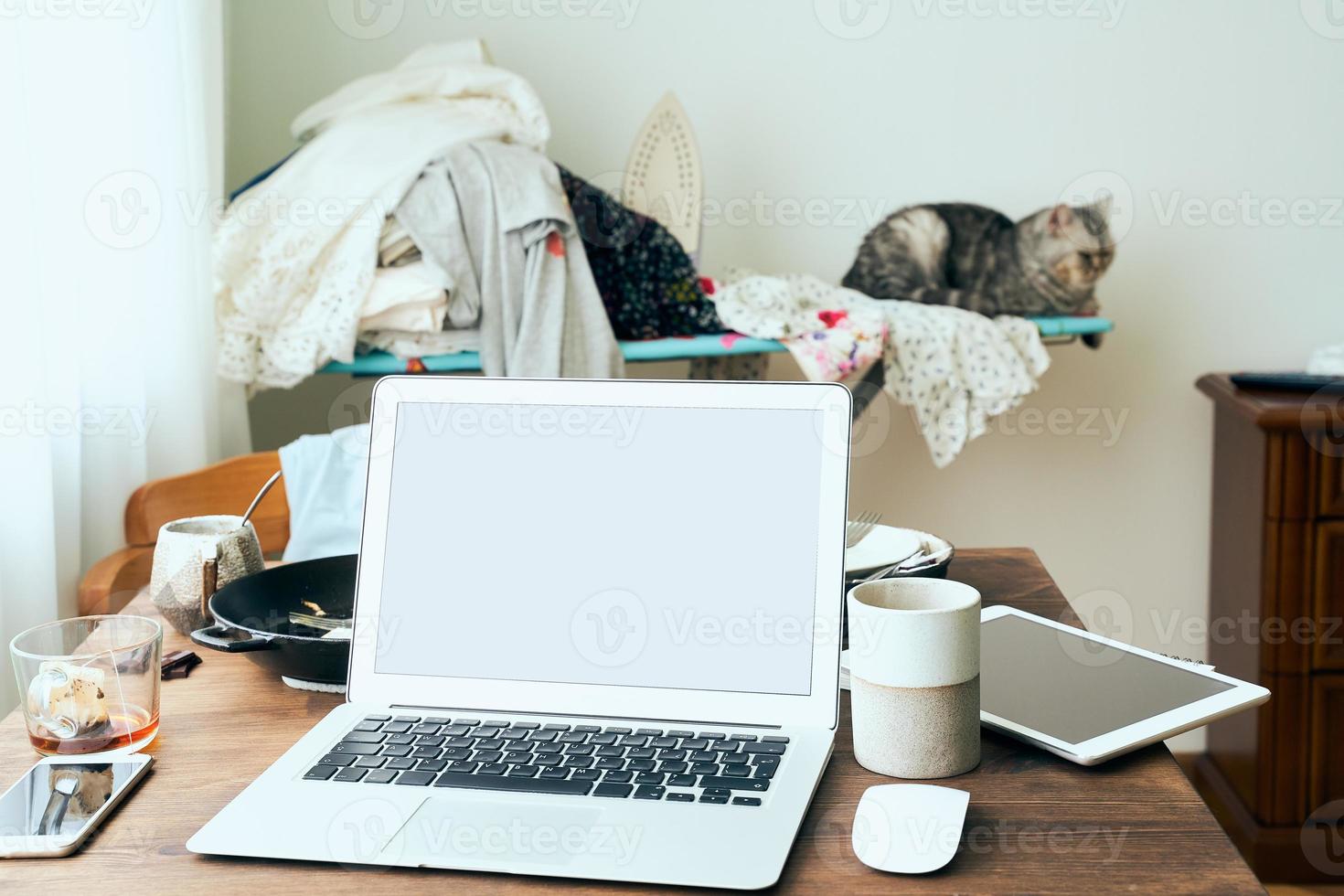 Freelance Desk with laptop in mess at home apartment. Quarantine, self-isolation, sociophobia photo