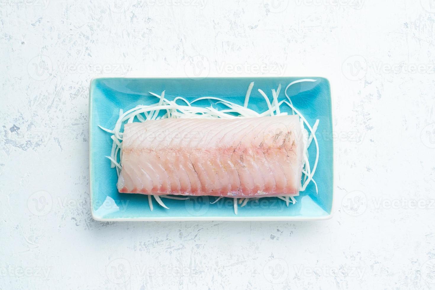 Fillet of raw white walleye fish on a blue plate on a white background. photo