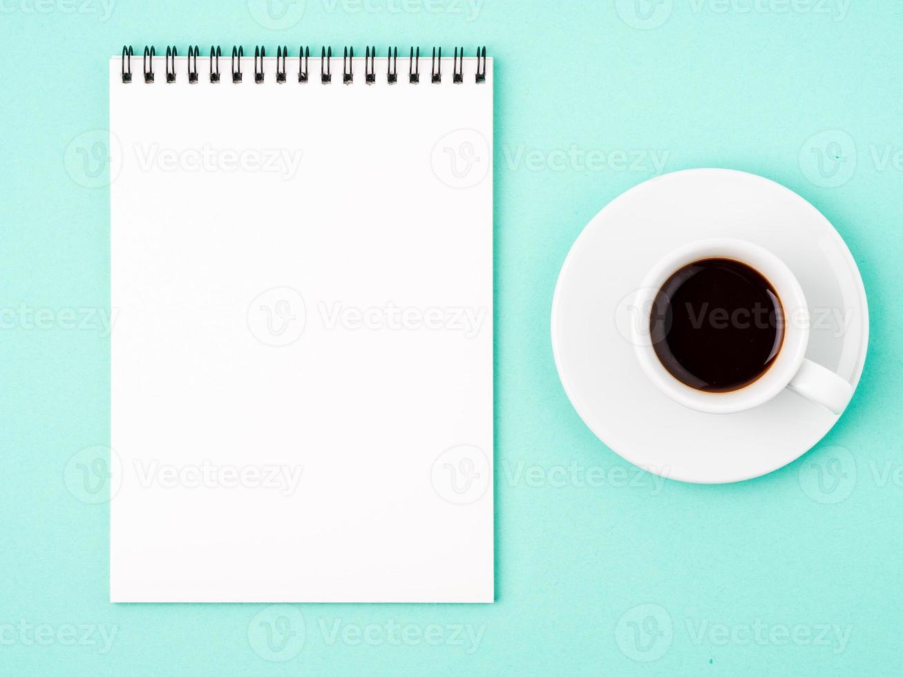 Notepad open with white blank page for writing idea or to-do list, a Cup of coffee on bright blue background photo