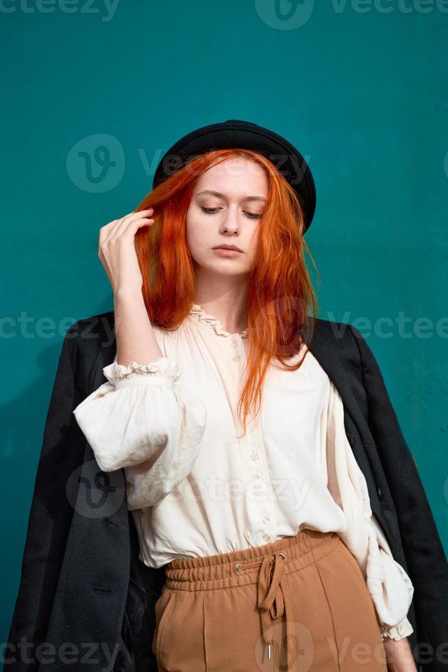 Redhead woman is resting against bright green wall. photo