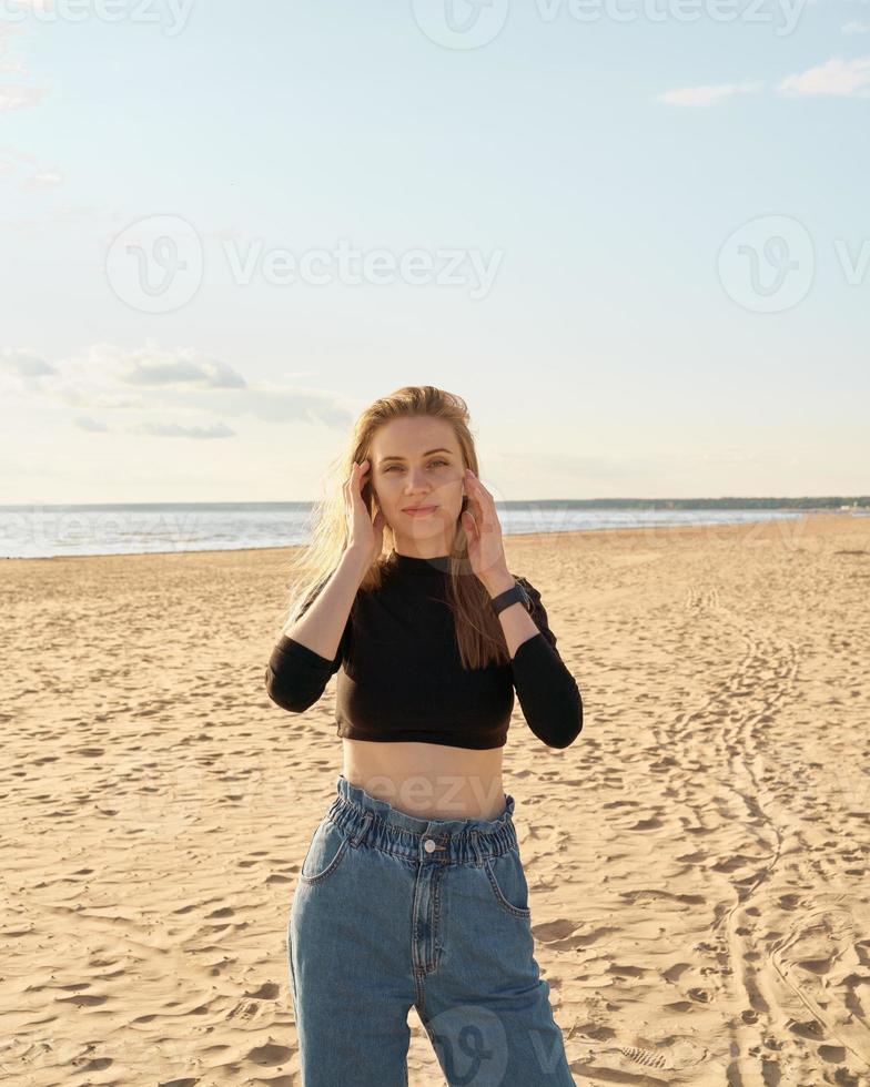 Beautiful woman standing on beach at sunset in evening. Pretty female photo