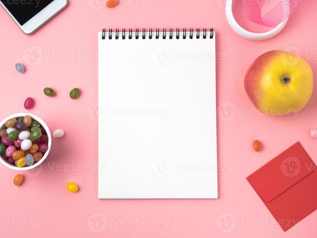 open notebook with a clean white sheet, caramel, lollipops, telephone, apple photo