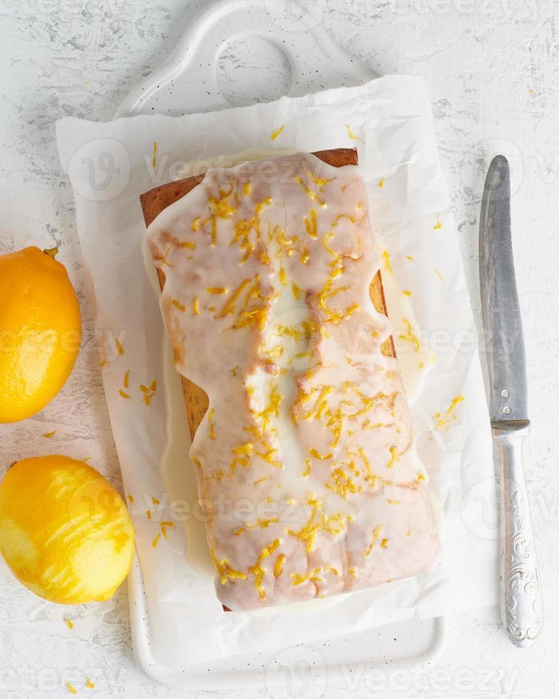 Lemon bread coated with sugar sweet icing. Whole loaf. White background, top view, copy space photo