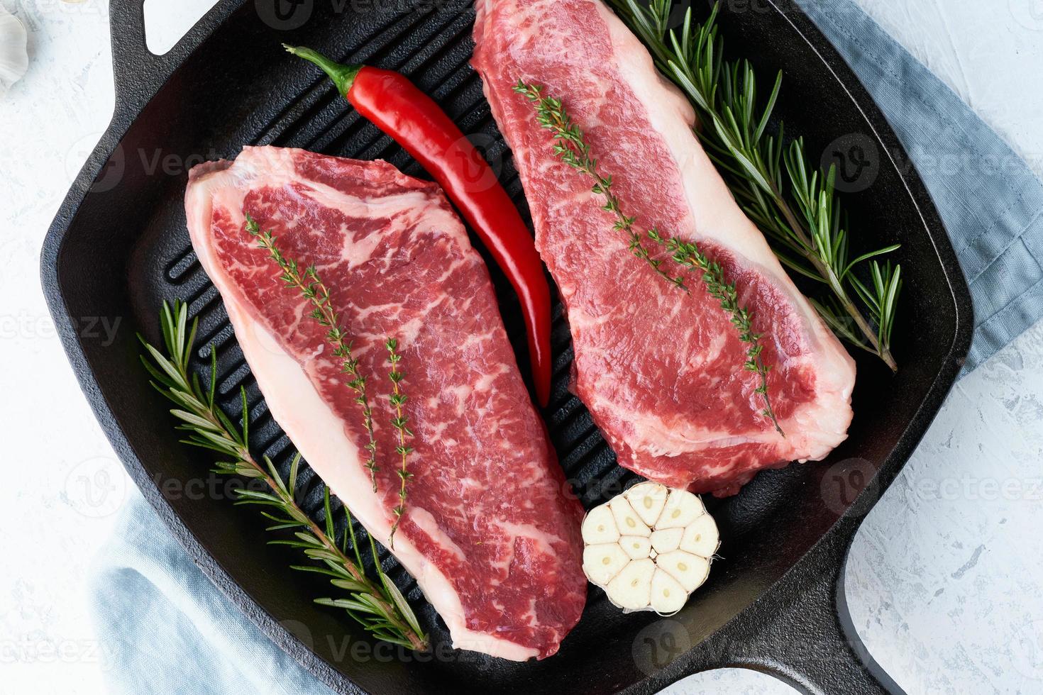 Two fresh raw big whole pieces of meat, beef fillet, marble striploin in cast-iron large pan. photo