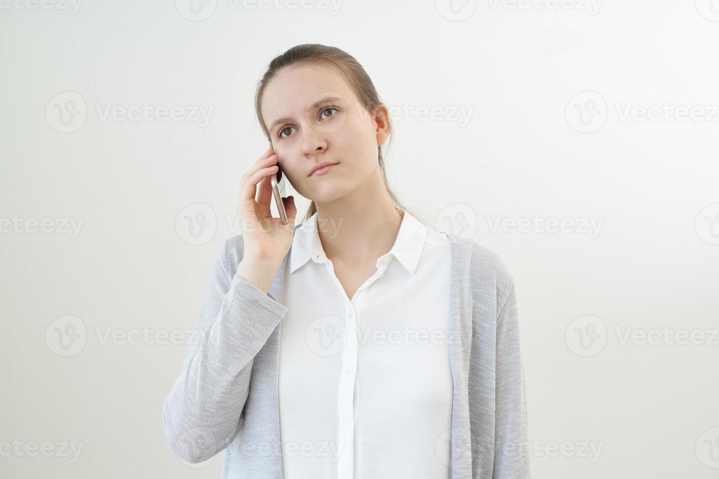 una mujer tranquila y sin emociones habla por teléfono, escucha a otra persona, no reacciona. foto