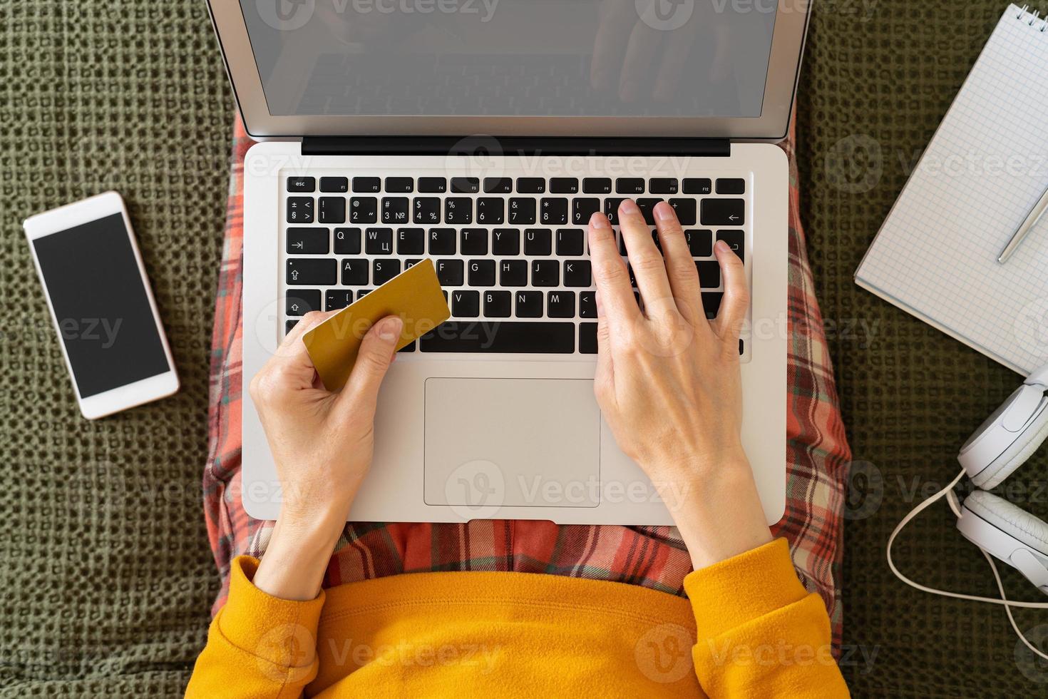 Online shopping concept. Unrecognizable woman sitting at bed, paying for purchases by credit card photo