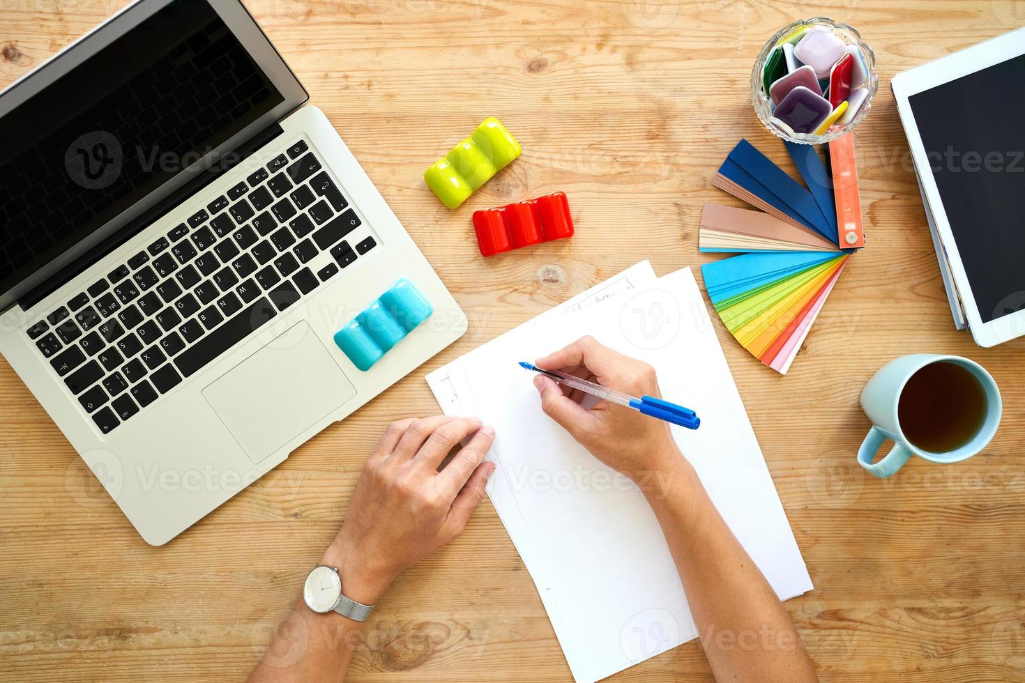 Designer workplace, top view. Home office - desk with laptop, hands with colourful set, photo