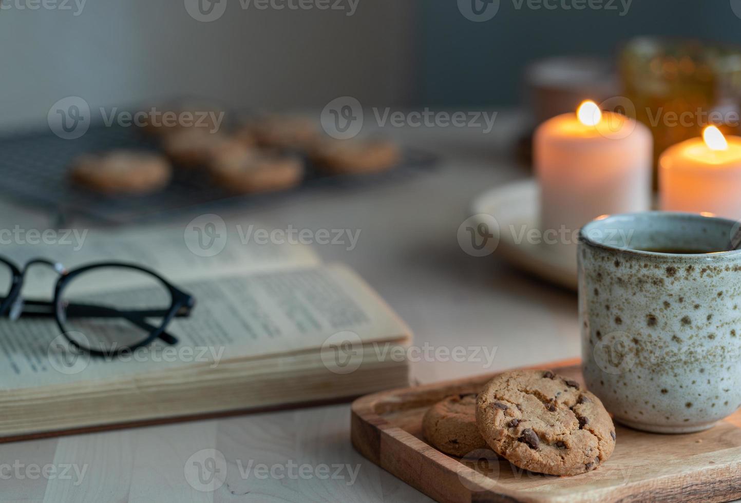 Reading book on cozy winter evening with candles, tea and cookies. photo