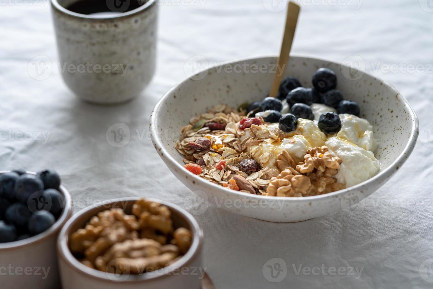 desayuno de estilo de vida saludable con muesli de granola y yogur en un tazón sobre fondo de mesa blanco foto
