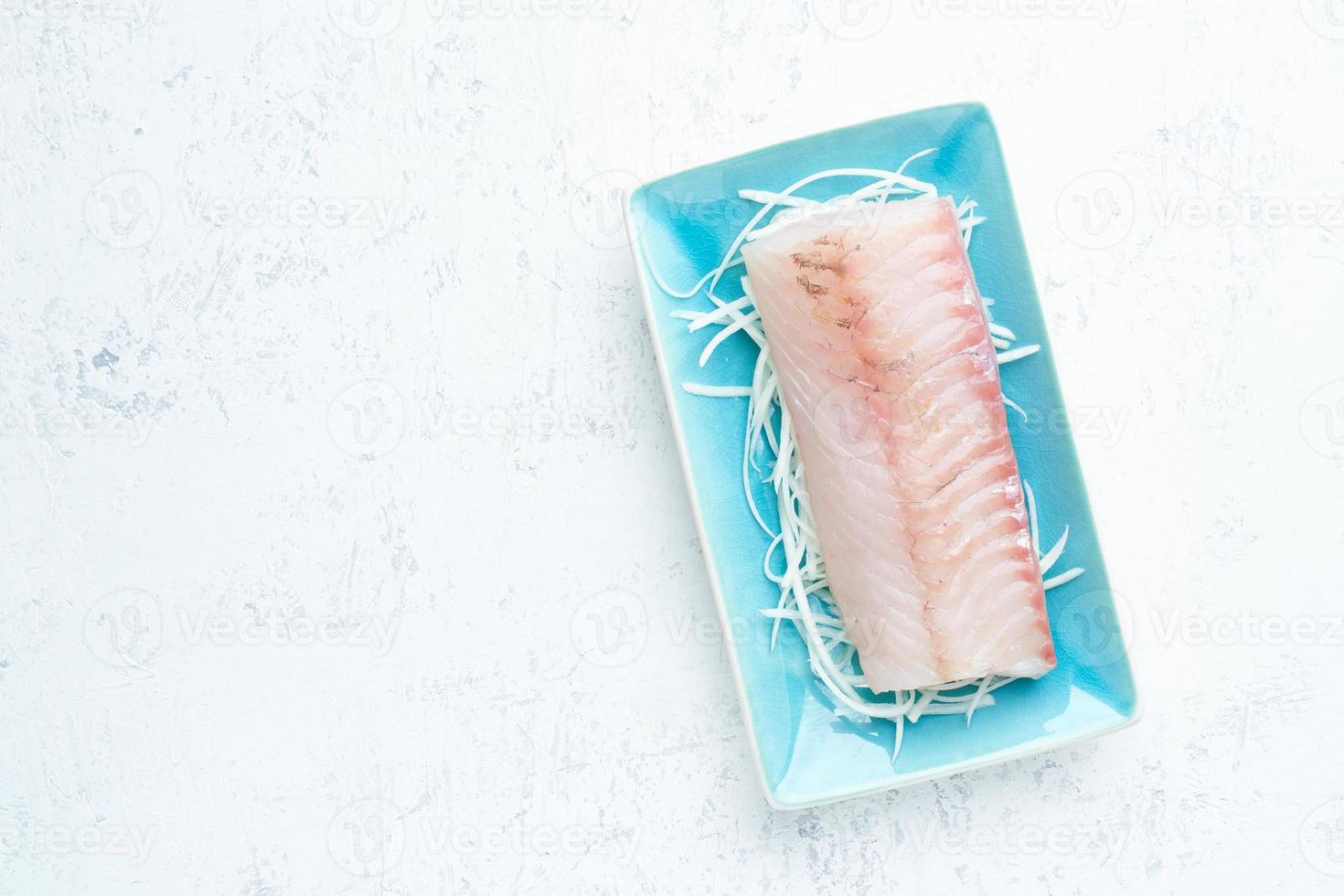 filete de pescado blanco crudo en un plato azul sobre un fondo blanco. vista superior, espacio de copia. foto