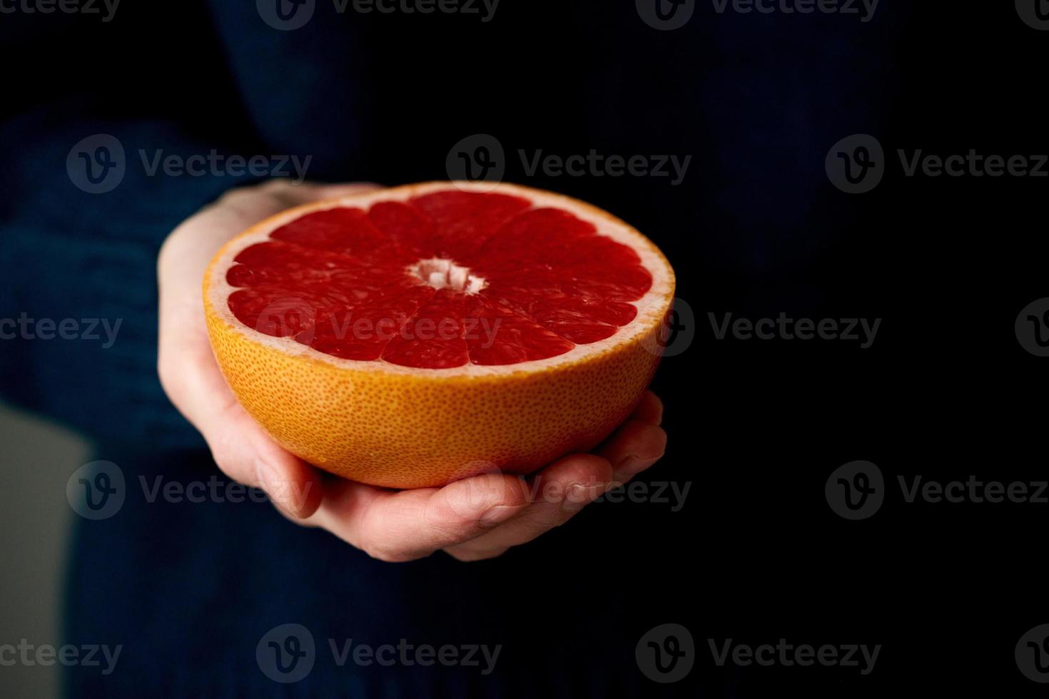 Close-up of woman's hand holding fresh halved red bright citrus fruit grapefruit photo