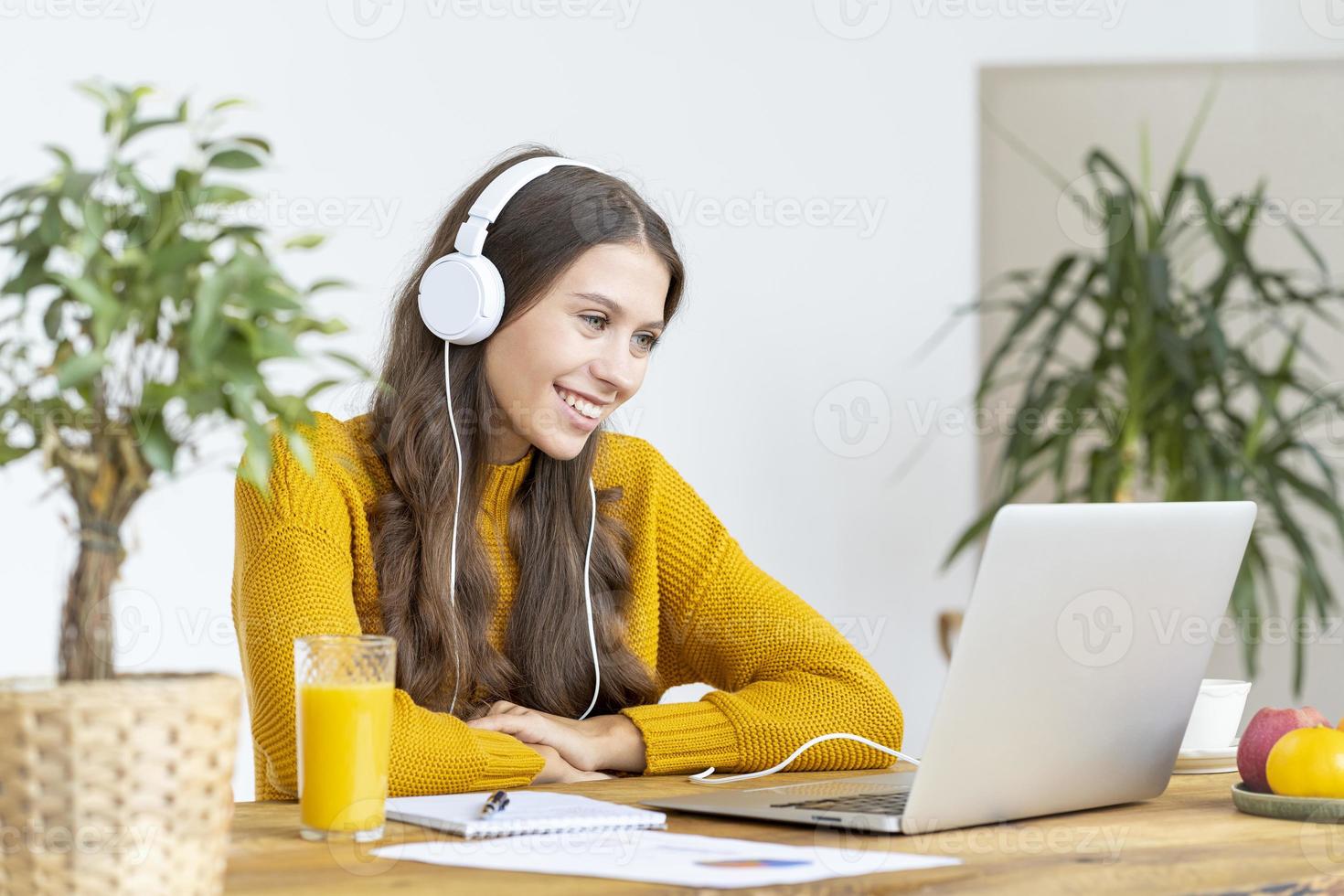 Young girl with headphones talking on conference calls, waving hand, smiling. photo