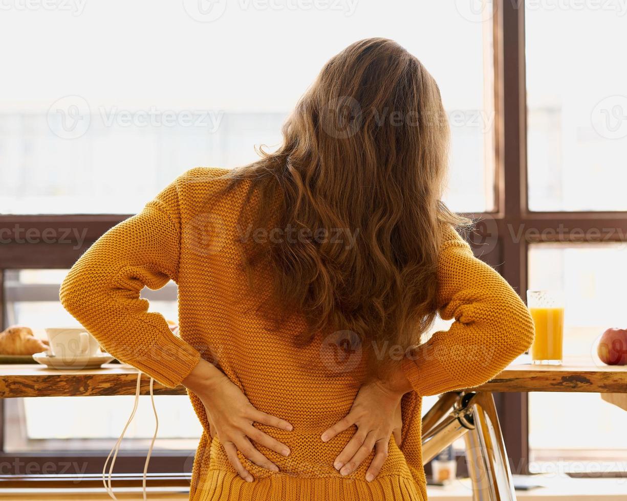 Back view of faceless young woman touching back feeling backache, discomfort photo