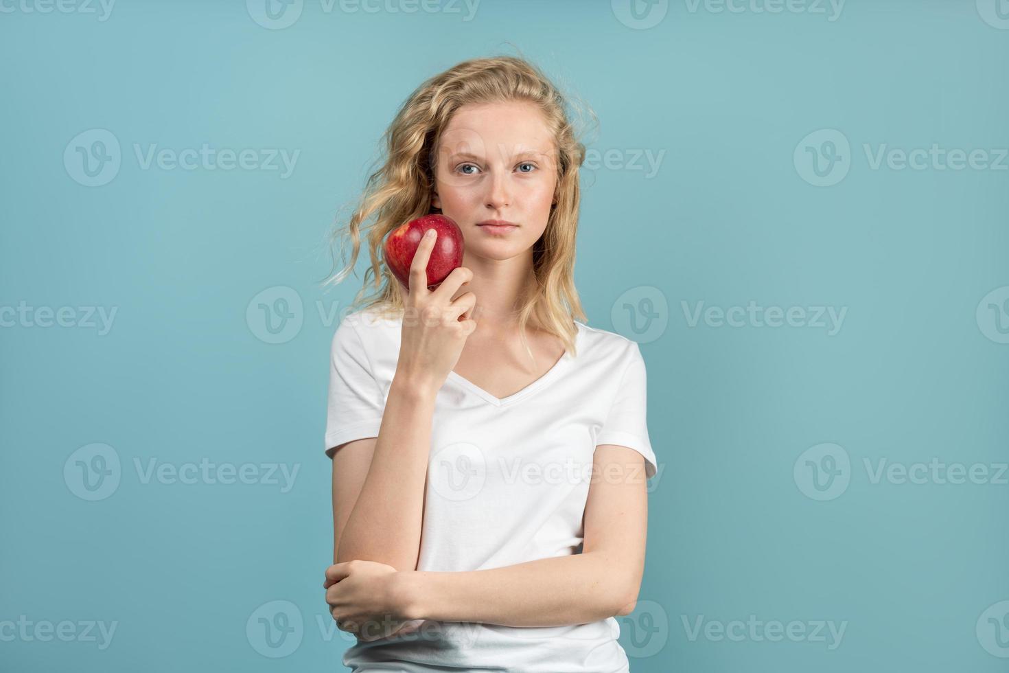 hermosa mujer joven con piel limpia y fresca sin maquillaje con cabello largo y rizado sosteniendo manzana foto