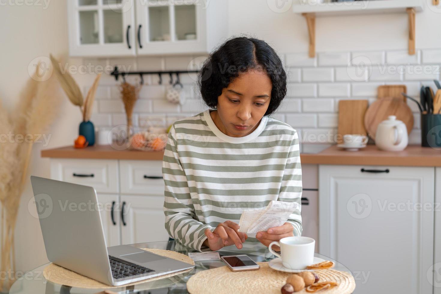 African-american female paying bills. Dealing with expenses on smartphone. Cutting back on spending photo