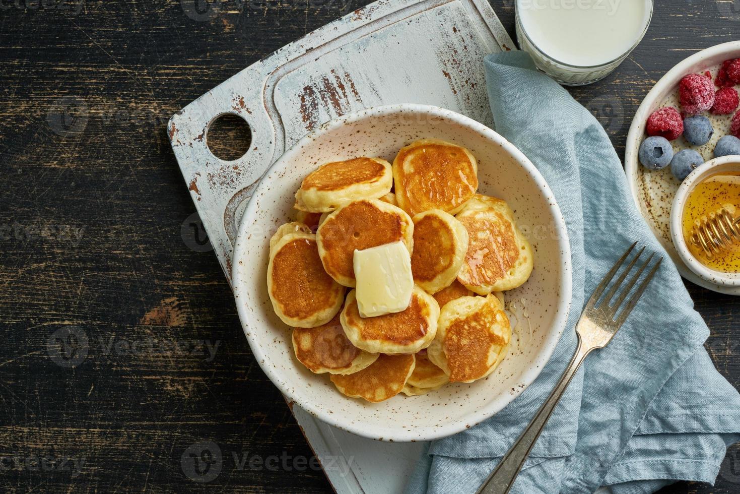 Pancakes cereal, tiny thin funny crumpet, children's food. Breakfast with drink, dark table photo