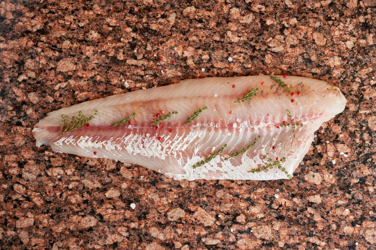 filete de pescado crudo fresco de lucioperca sobre una mesa de mármol marrón oscuro. vista superior foto