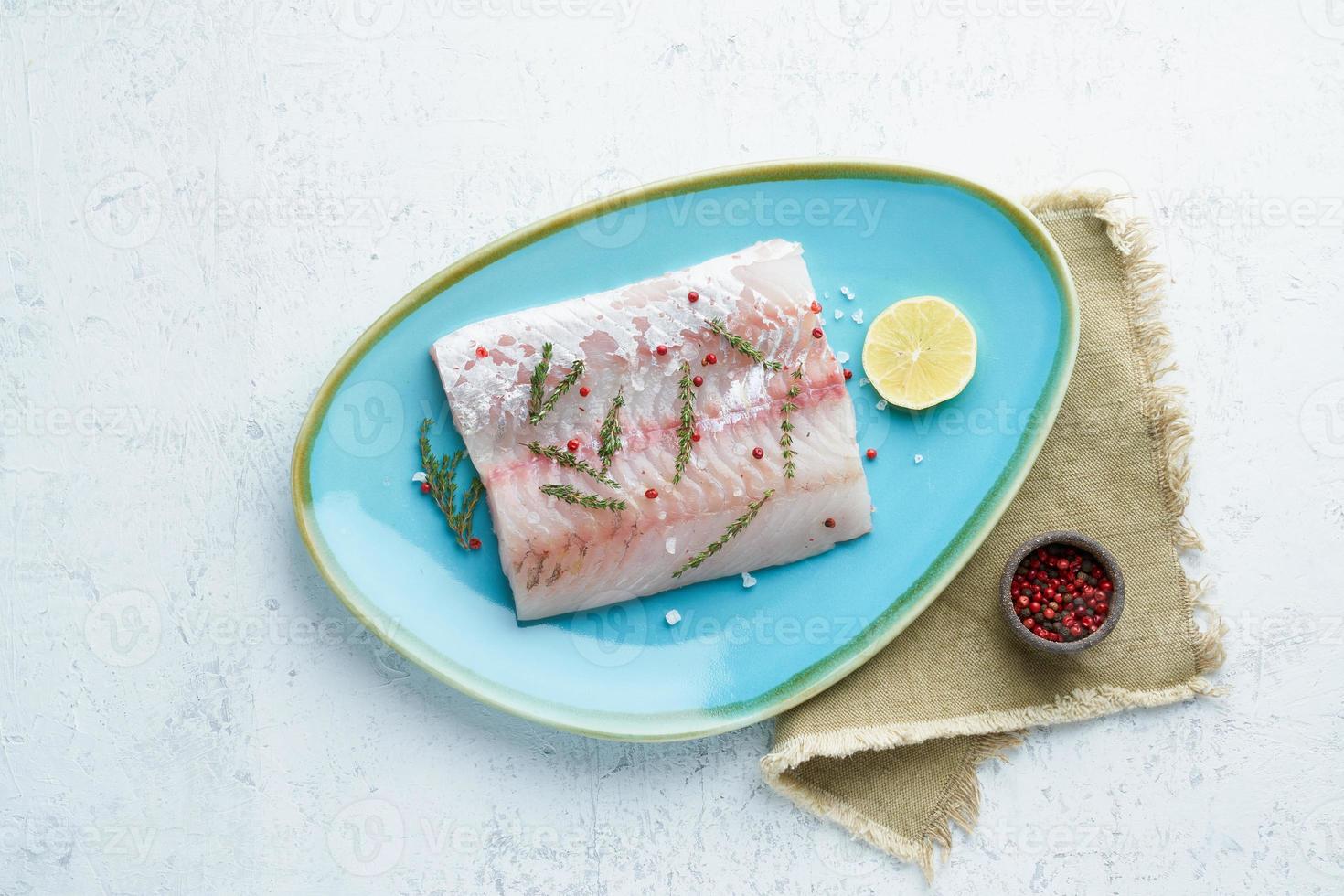 Fillet of raw white walleye fish on a blue plate on a white background. Whole piece of fresh fish photo