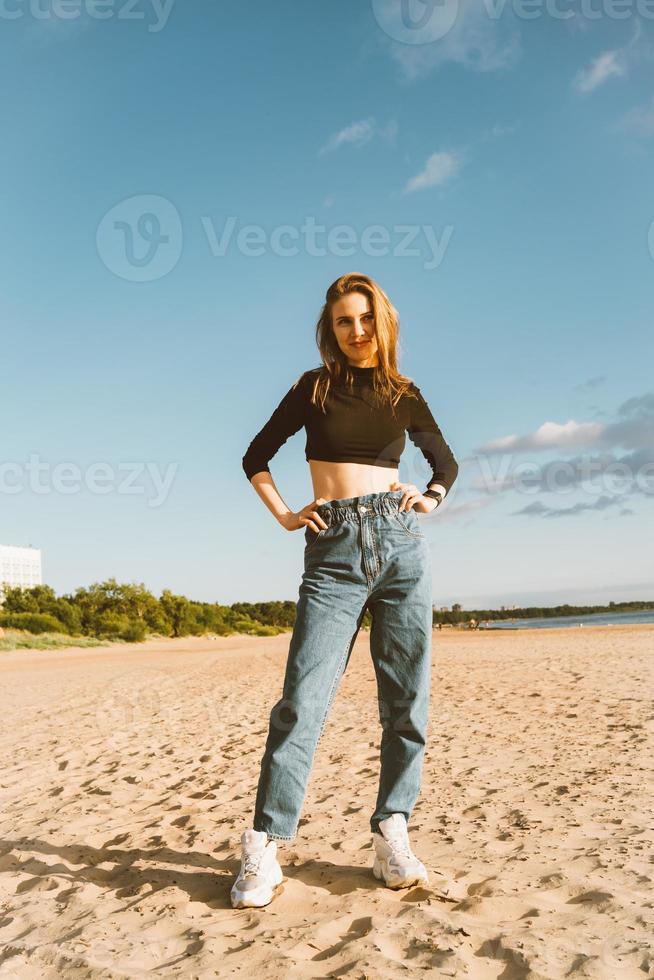 Full length beautiful woman standing on beach at sunset in evening. Pretty female photo