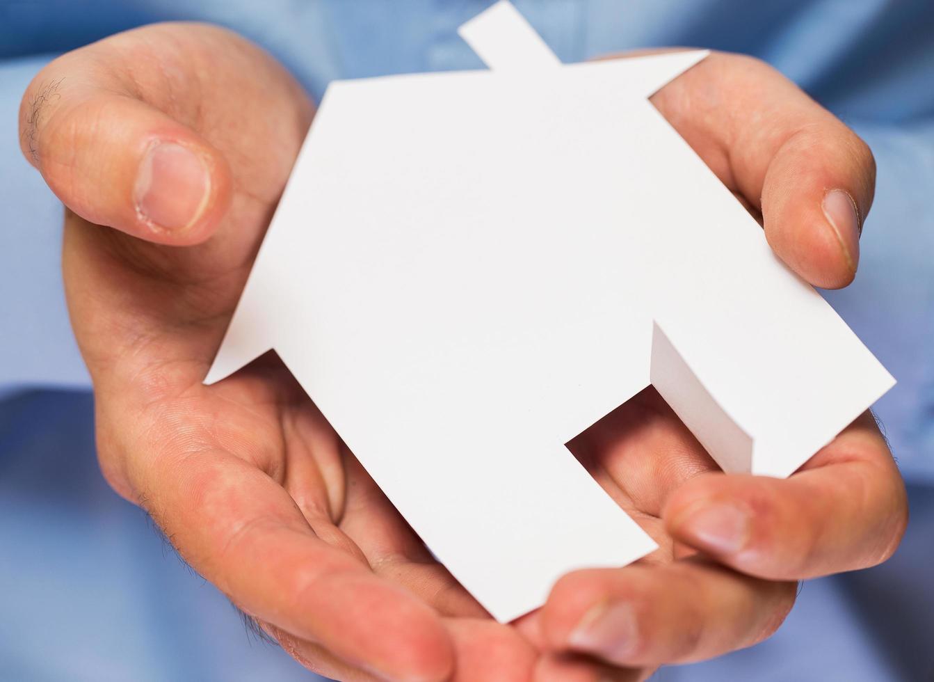 Man holding paper house in his hands photo