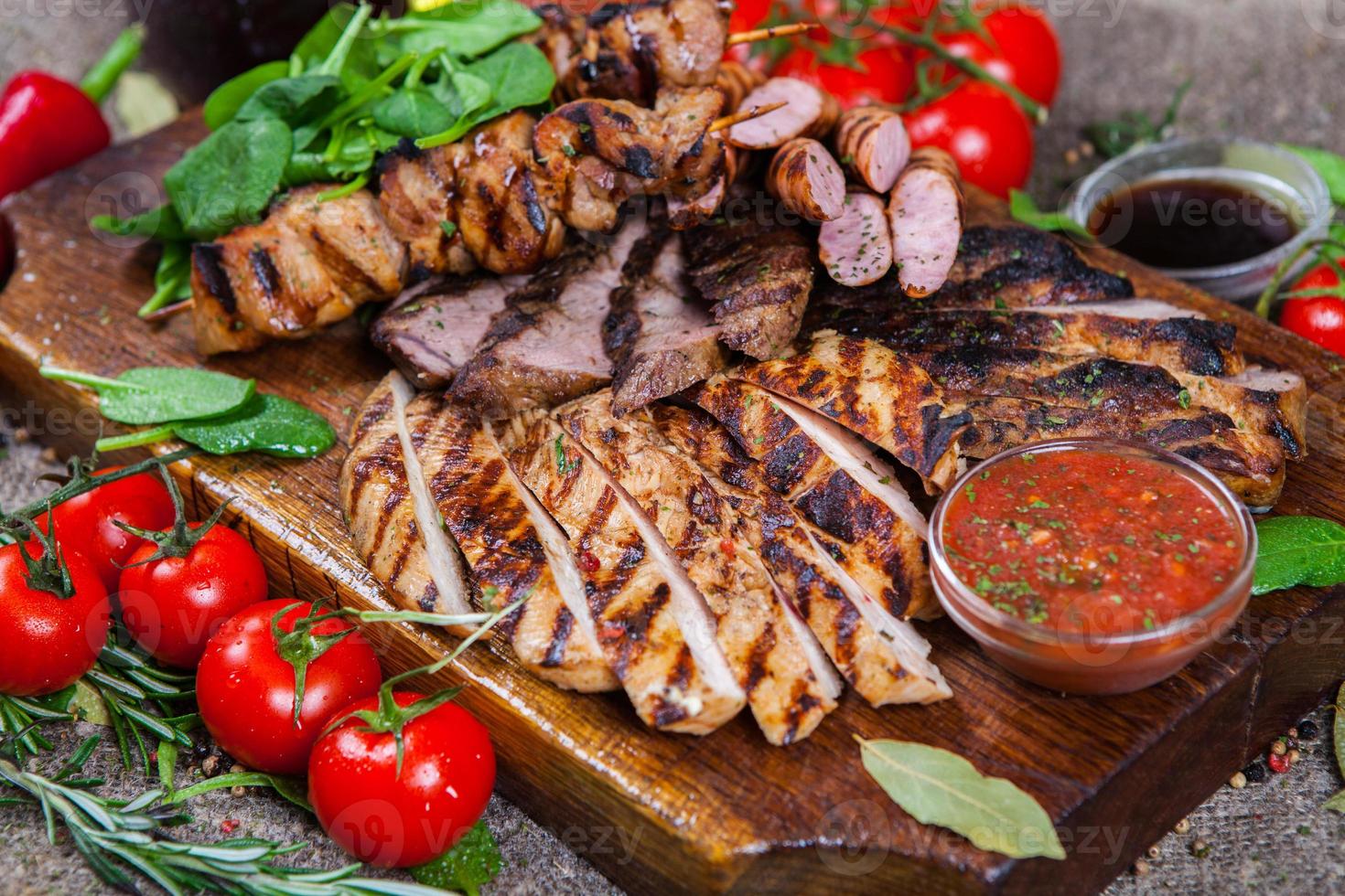 Mixed grilled meat platter. Assorted delicious grilled meat with vegetable. Mixed grilled meat with pepper sauce and vegetables. photo