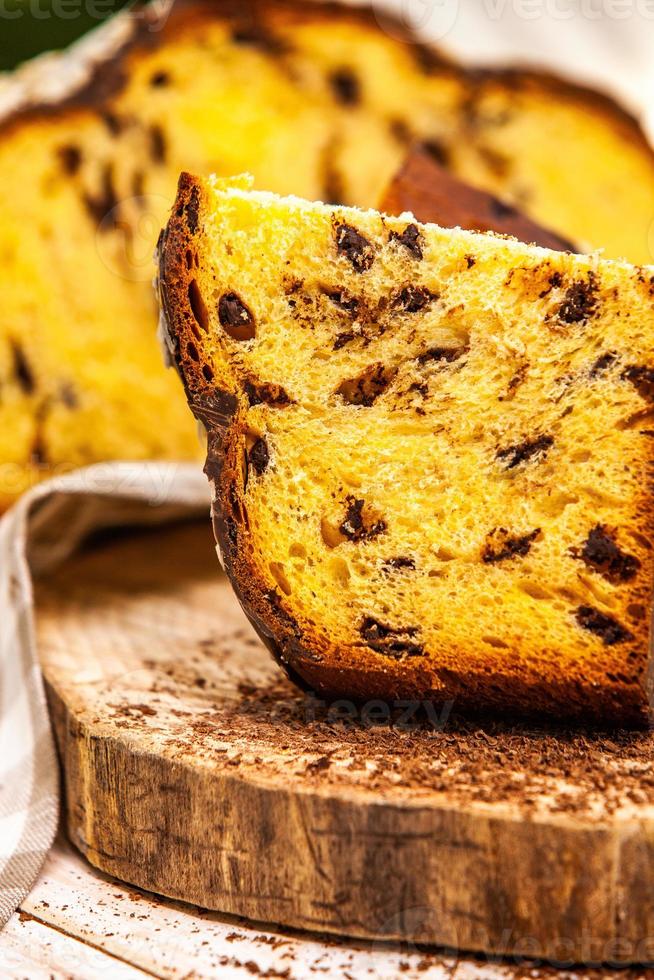 panettone casero. pan dulce tradicional italiano. panettone con una rodaja servido en una mesa de madera. foto