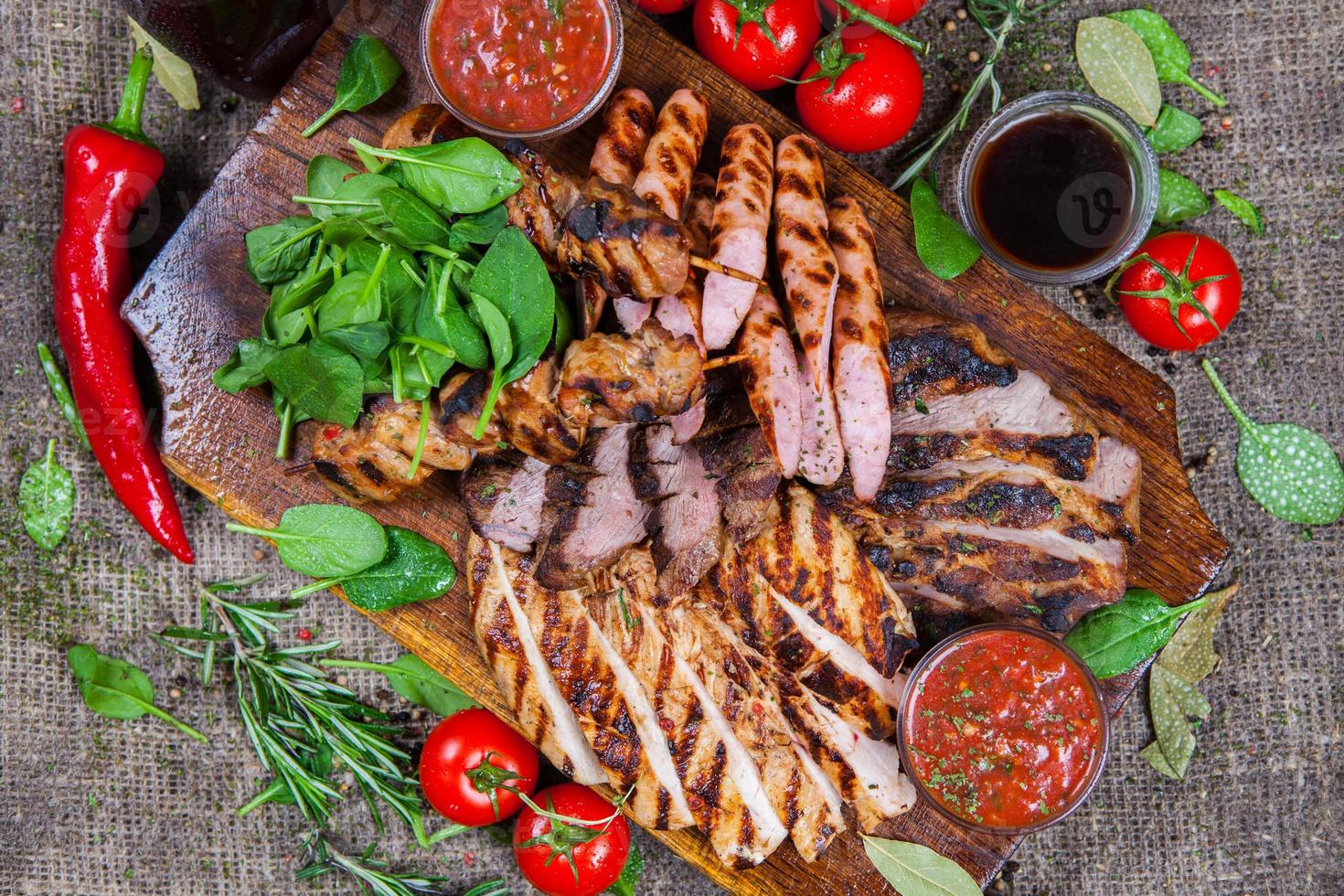 Plato mixto de carnes a la brasa. Surtido de deliciosas carnes a la parrilla con vegetales. Carne mixta a la parrilla con salsa de pimienta y verduras. foto