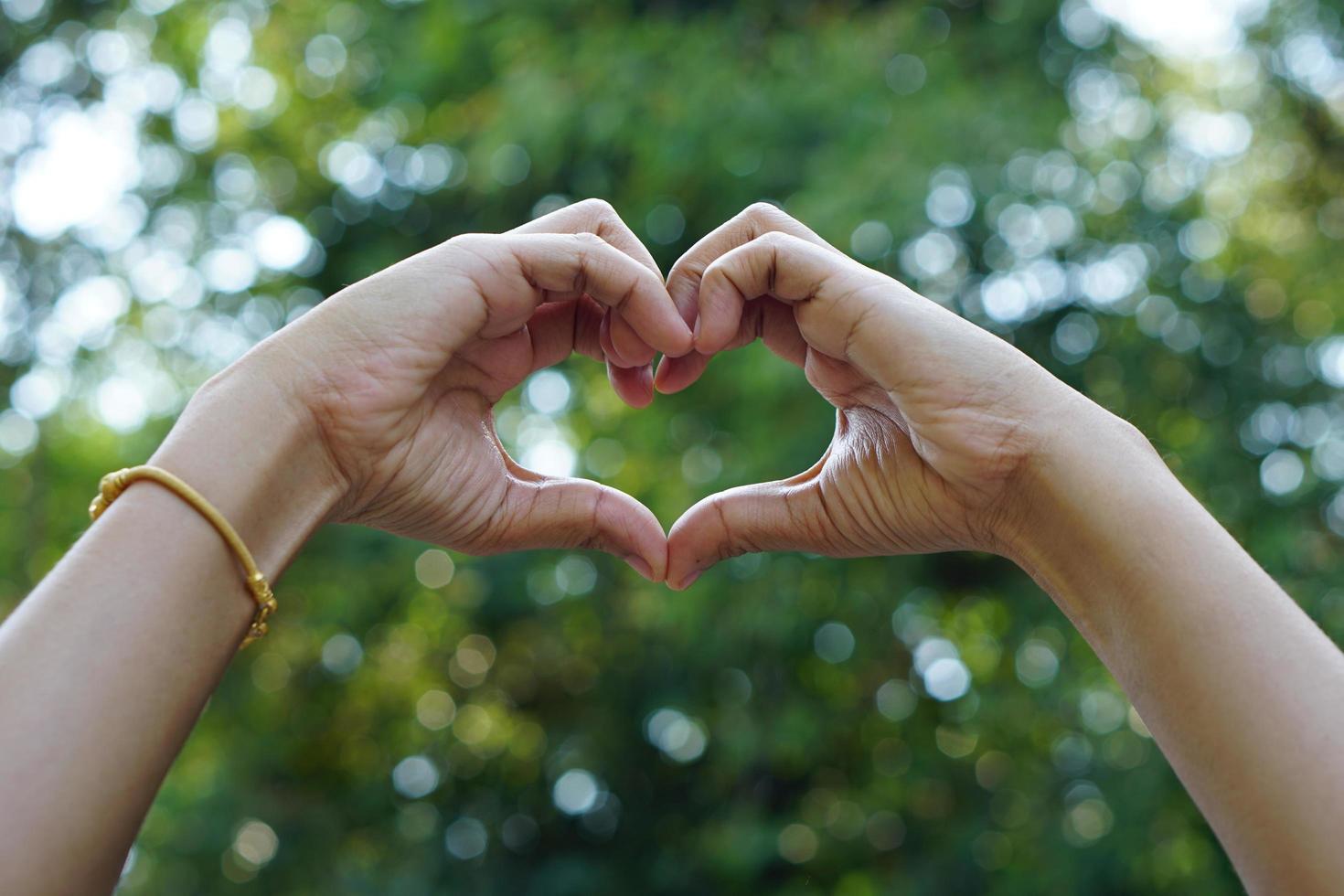 mano humana corazón verde bokeh fondo foto