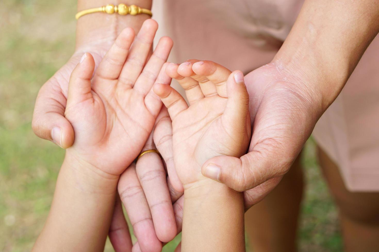 Mother's hand holding a little girl's hand on bokeh background. Love and family concept. photo