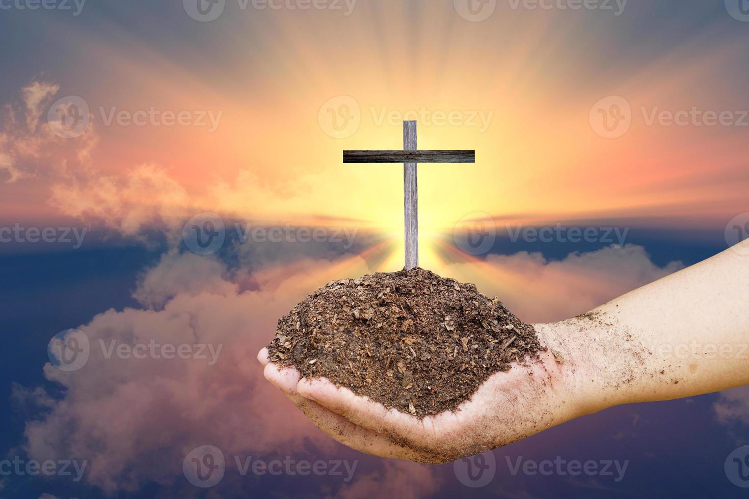 cross in the human hand on the light background of the sun photo