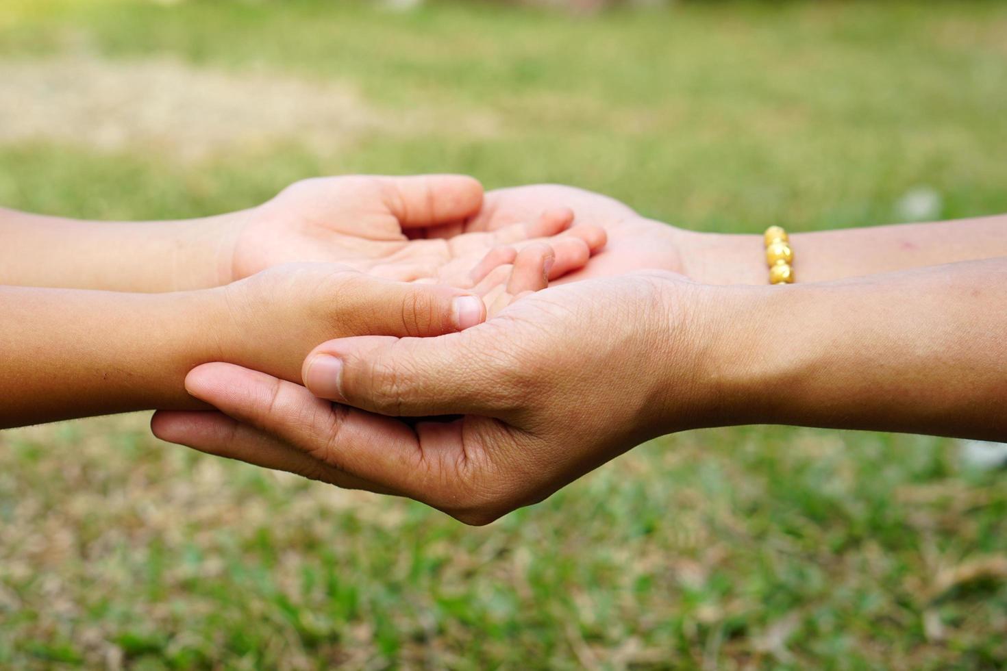 Mother's hand holding a little girl's hand on bokeh background. Love and family concept. photo