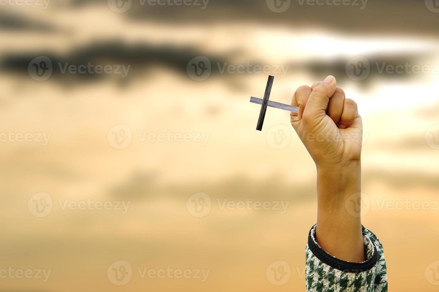 cross in the human hand on the light background of the sun photo