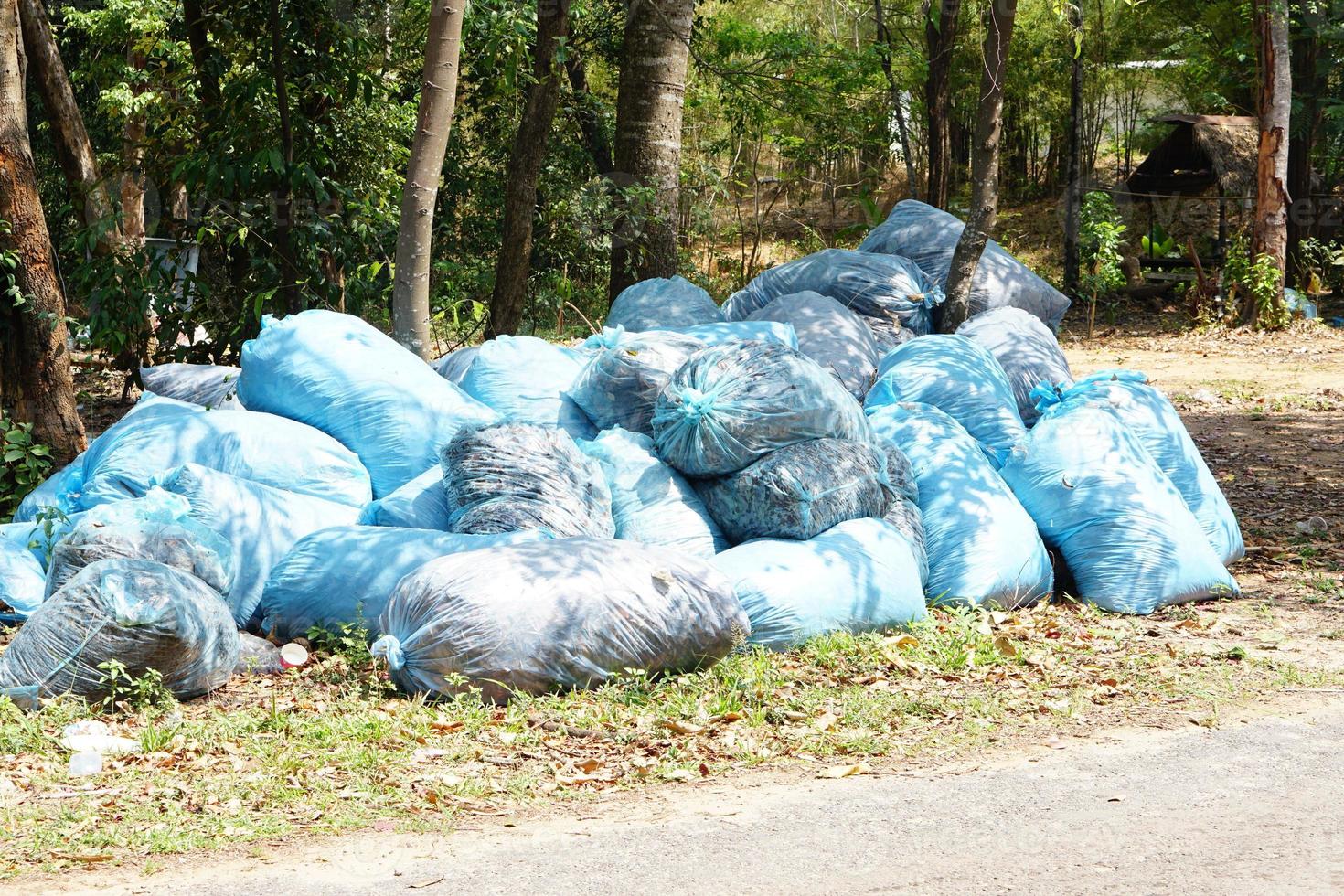 Blue trash bags are thrown in the forest. photo