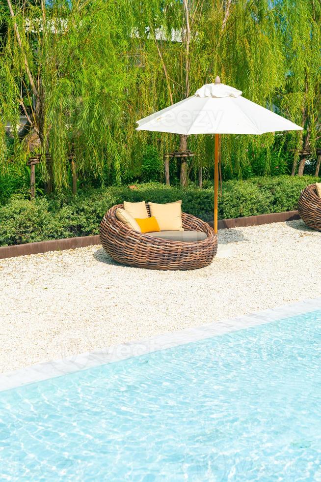 outdoor patio chair with pillow and umbrella around swimming pool photo