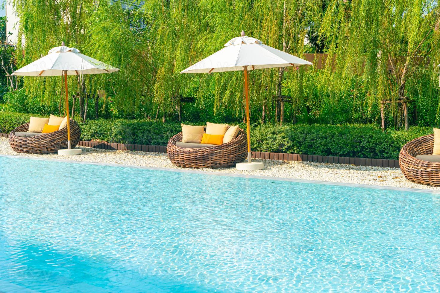 outdoor patio chair with pillow and umbrella around swimming pool photo