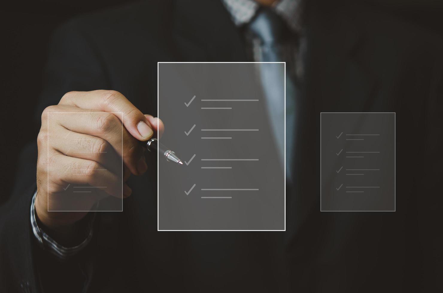 businessman holding pen to check business digital documents on virtual screen. photo