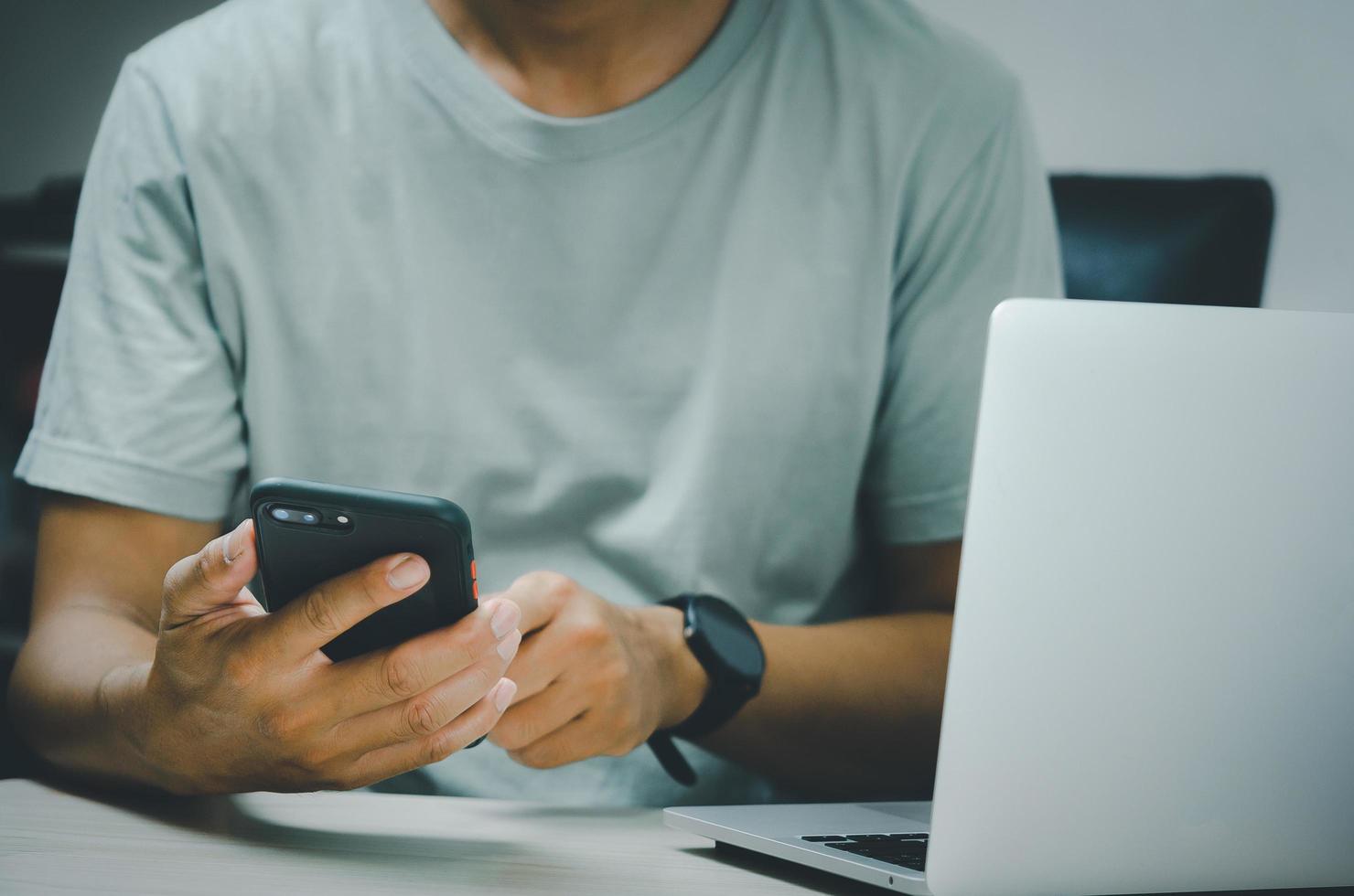 man hand holding smartphone and computer laptop to working technology searching internet, sending sms, using text messenger or online banking. photo