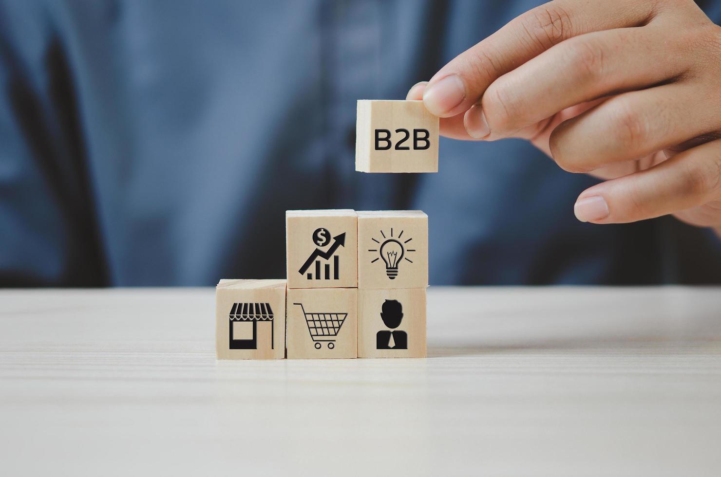 Hand put wooden cubes with  B2B Business to Business icons and symbols on table and copy space.Business concepts. photo