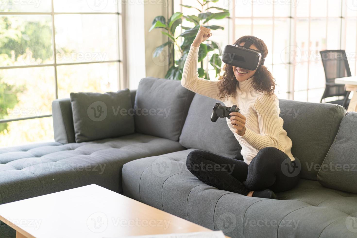 Mujer latina con un casco de realidad virtual en el sofá foto