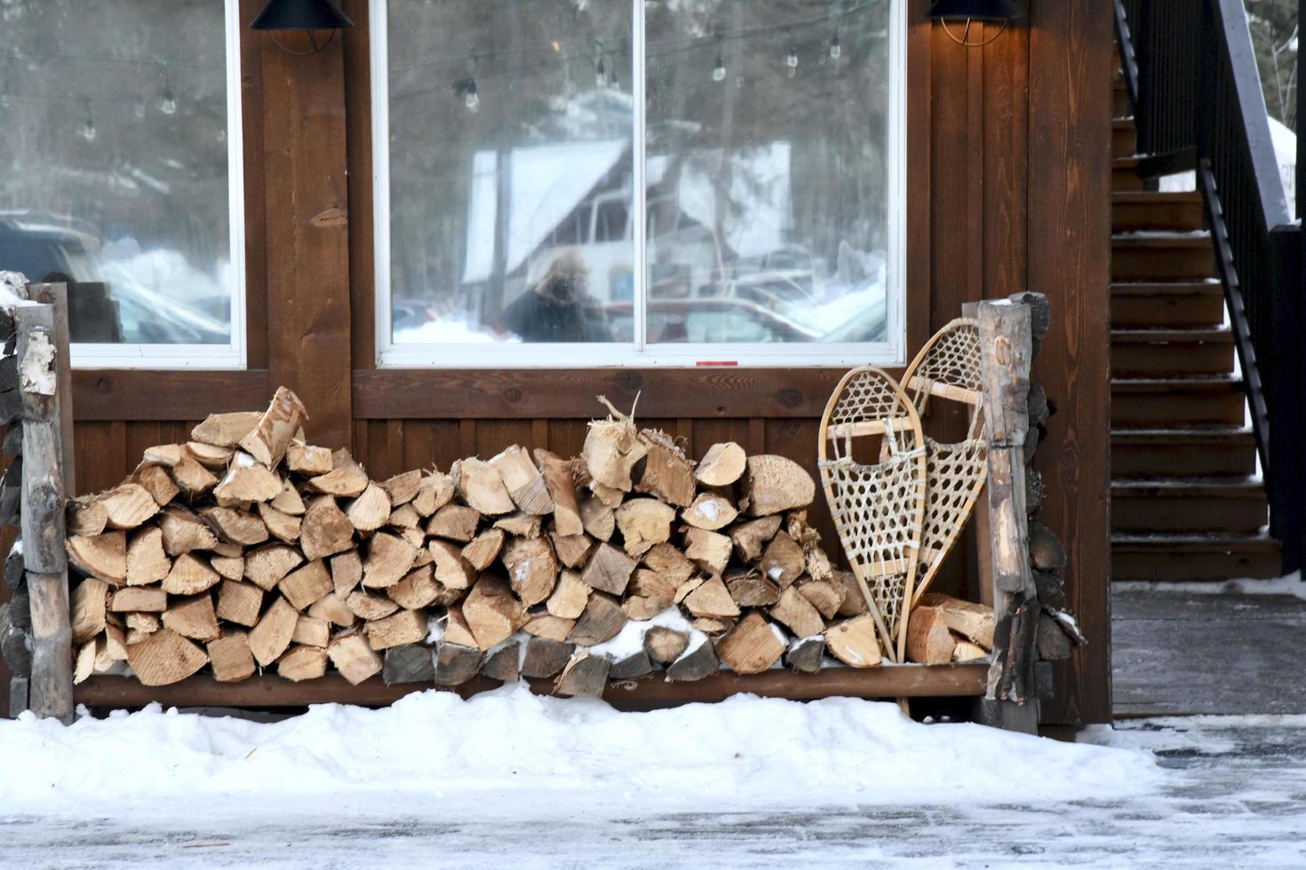 firewood and snow shoes sit outside a cabin photo