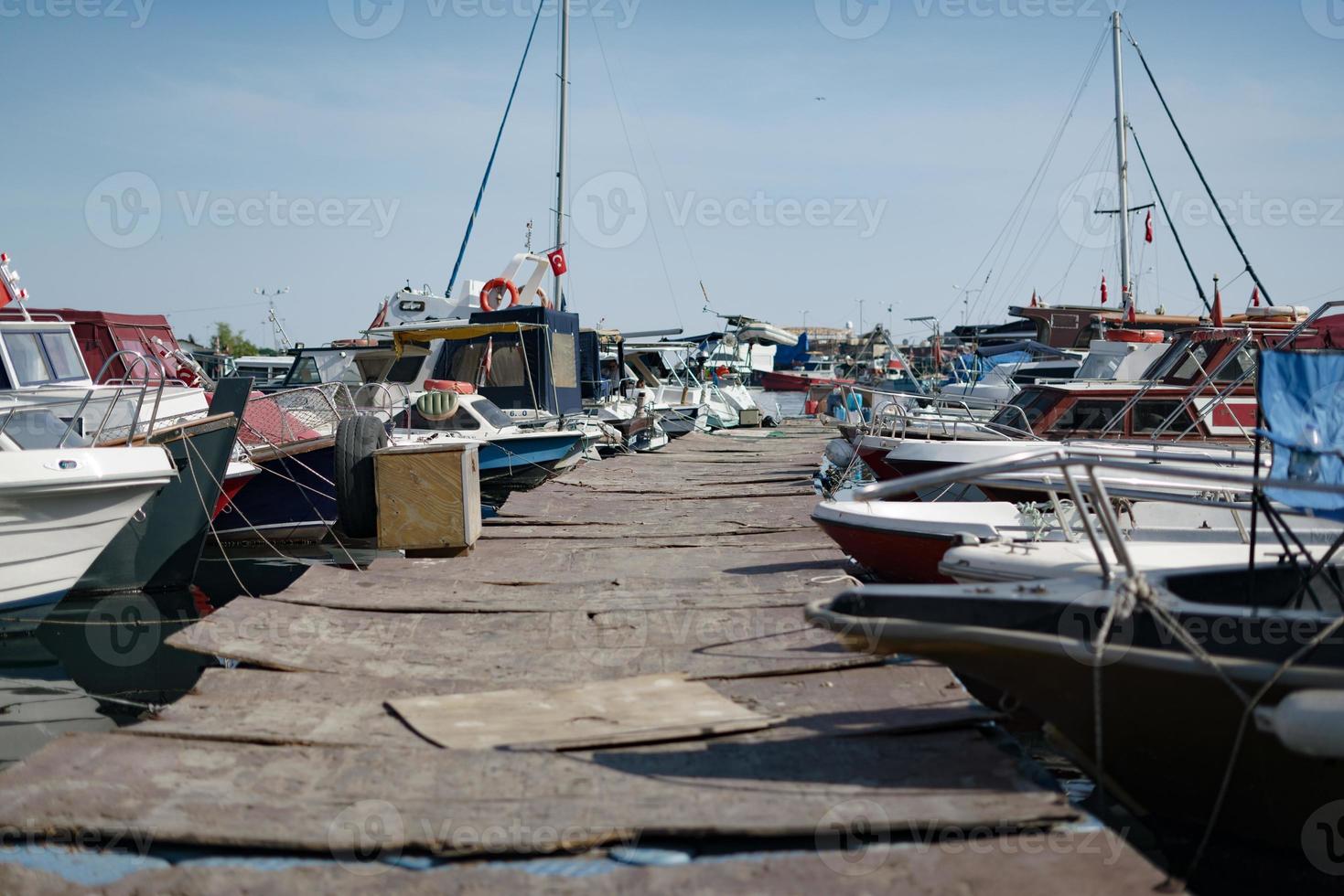 Various boats in the marina side by side on wooden port photo