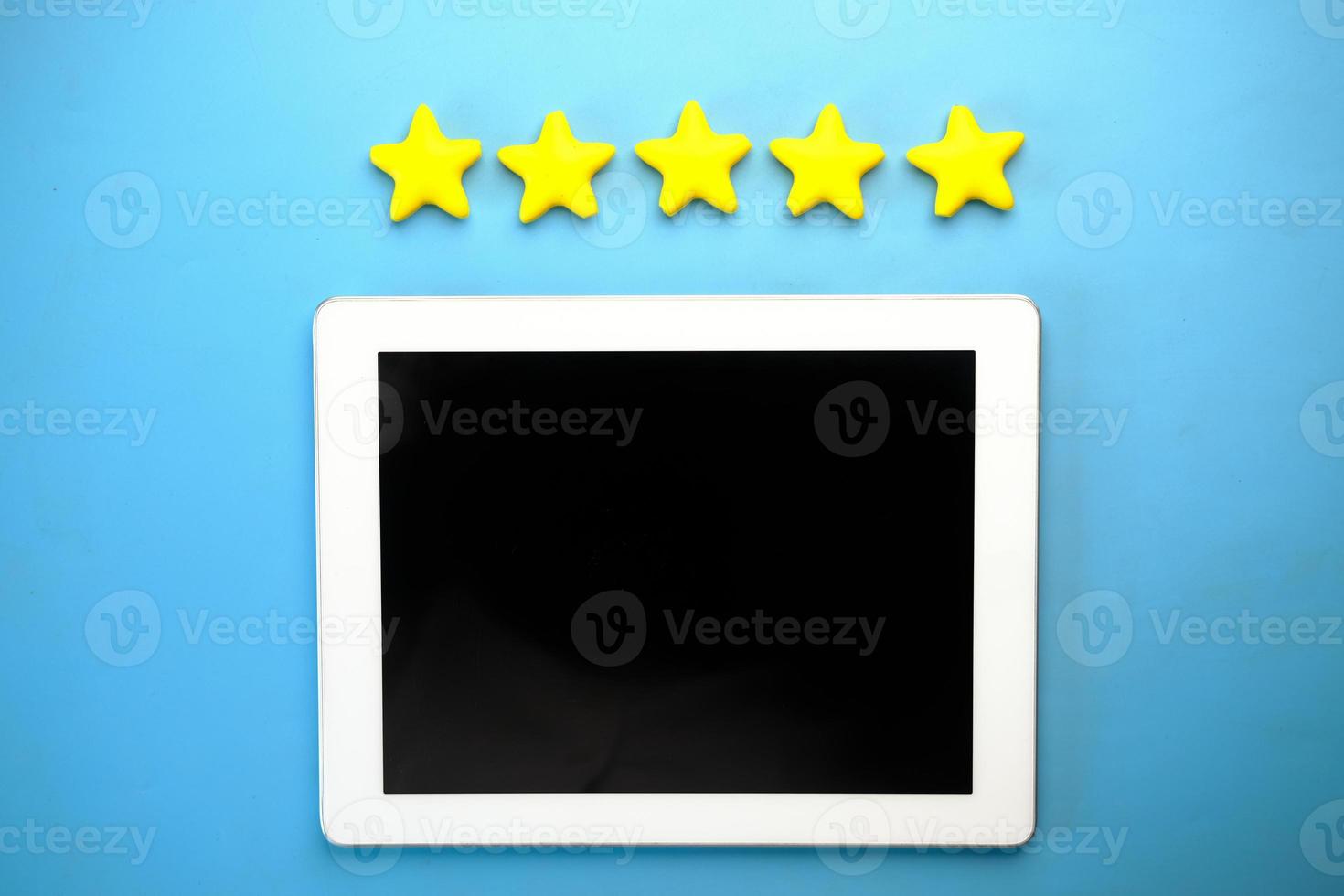 Customer review concept. Rating golden stars and digital tablet on blue photo