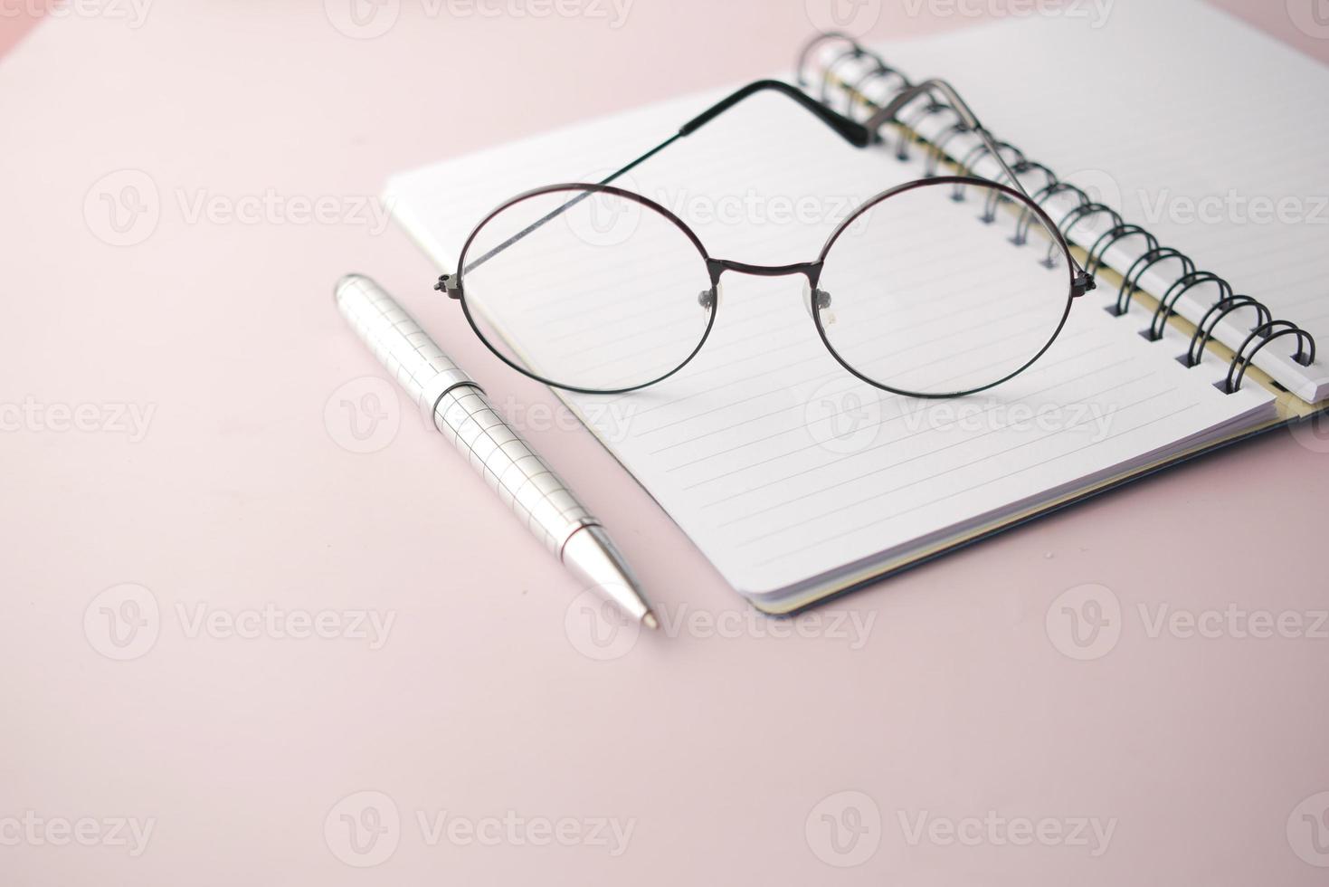 notepad, eyeglass and a pencil on wooden table photo