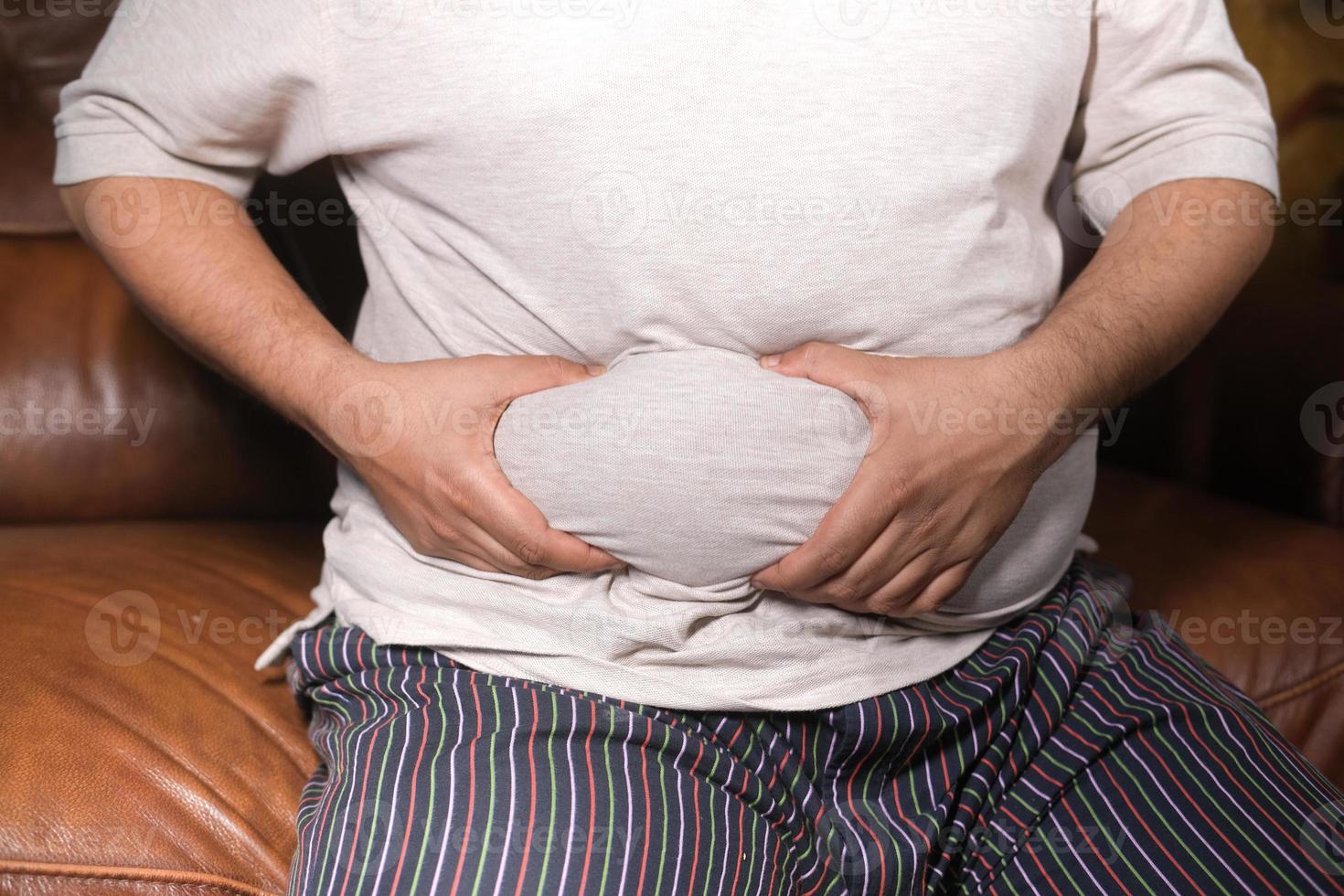 La mano del hombre sujetando el exceso de grasa abdominal, concepto de sobrepeso foto