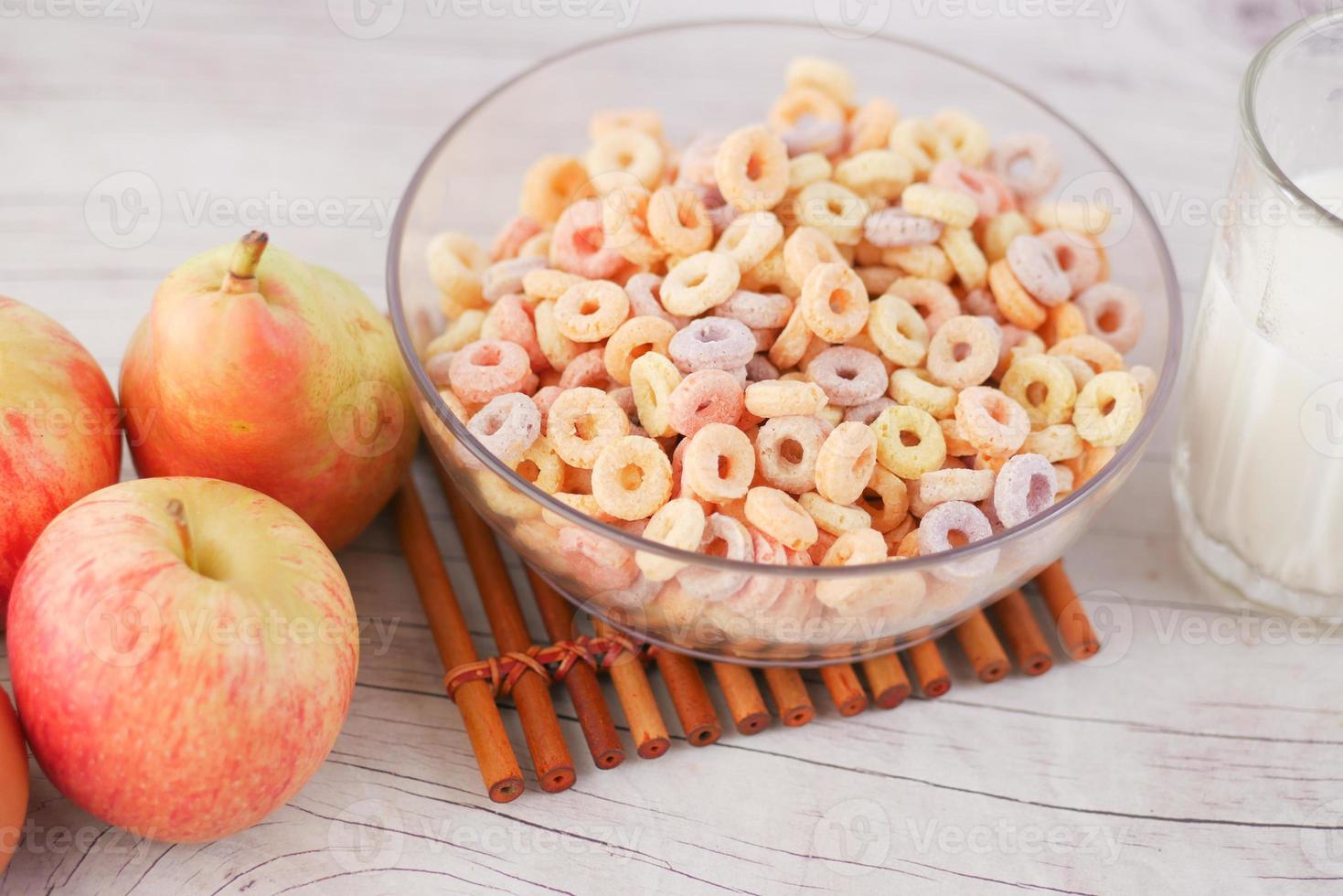 colorful cereal corn flakes in a bowl , apple and milk on table photo