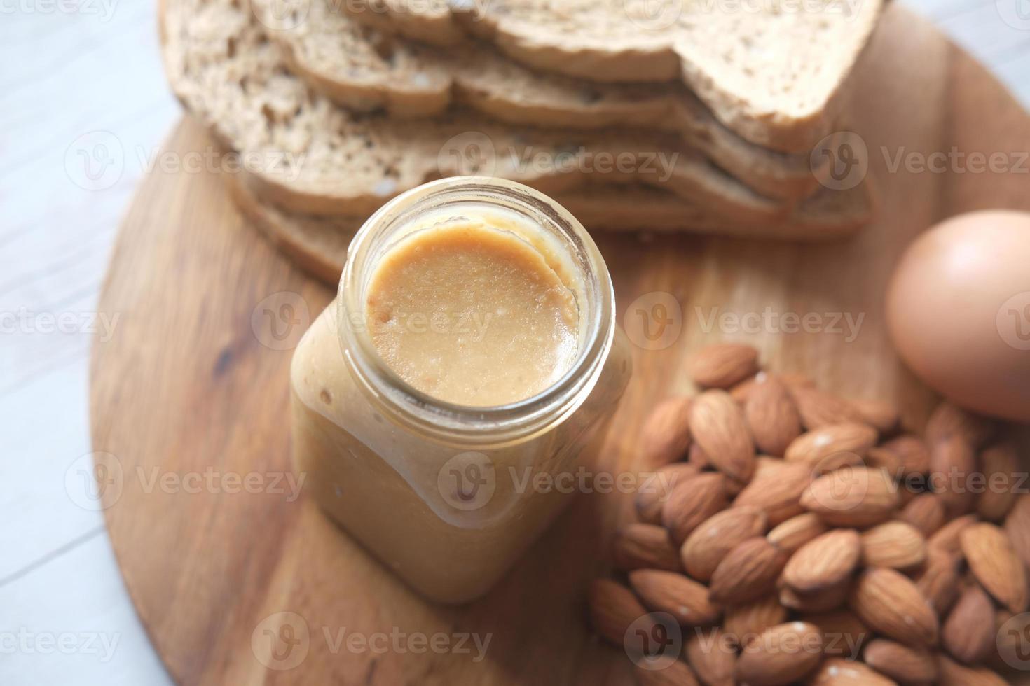 almond butter in a container , egg and bread on table photo