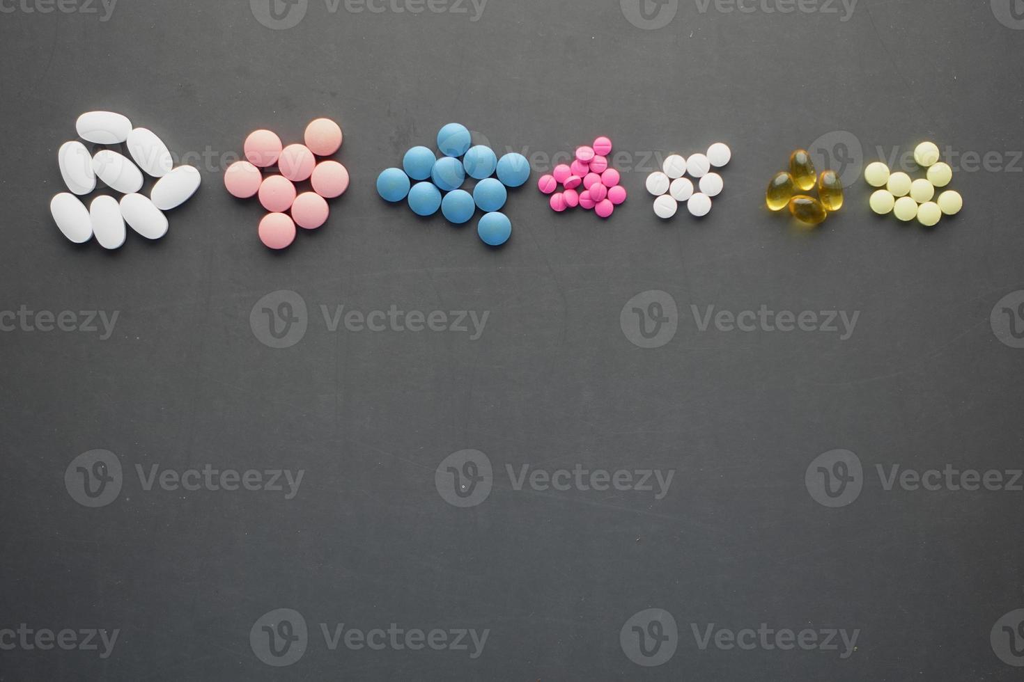 top view of any colorful pills and capsules on black background photo