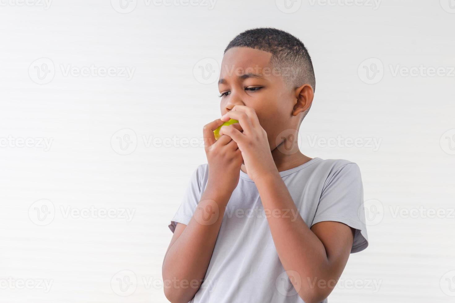 Child kid eating green apple fruit, Child playing and eating an apple in white wall living room photo