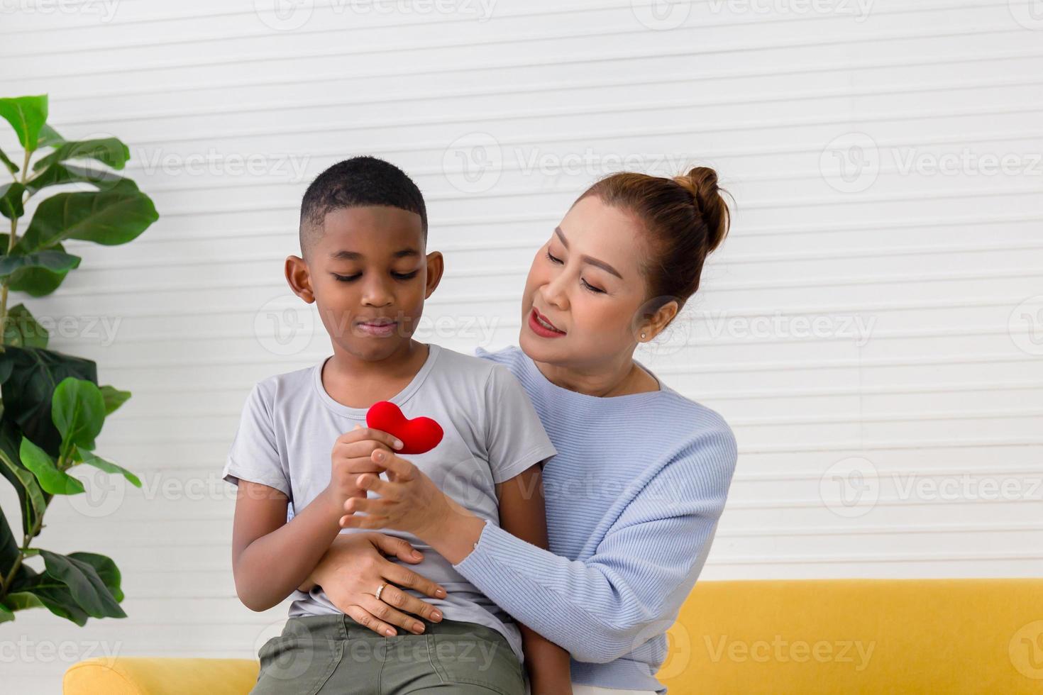 Grandson child congratulates grandmother on holiday and gives a heart shape, Grandmother and grandson playing cheerfully in living room photo