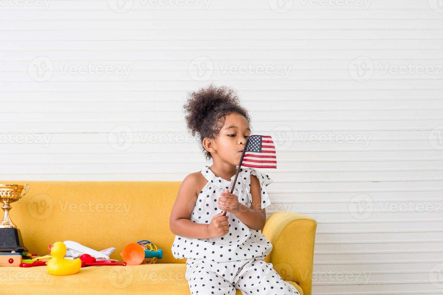 niña linda con una pequeña bandera nacional de estados unidos, niña jugando en la sala de estar foto